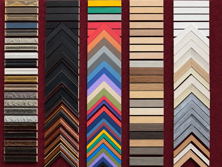 Wall of frame moulding samples in gilt, black, ornate, colourful and natural wood finishes
